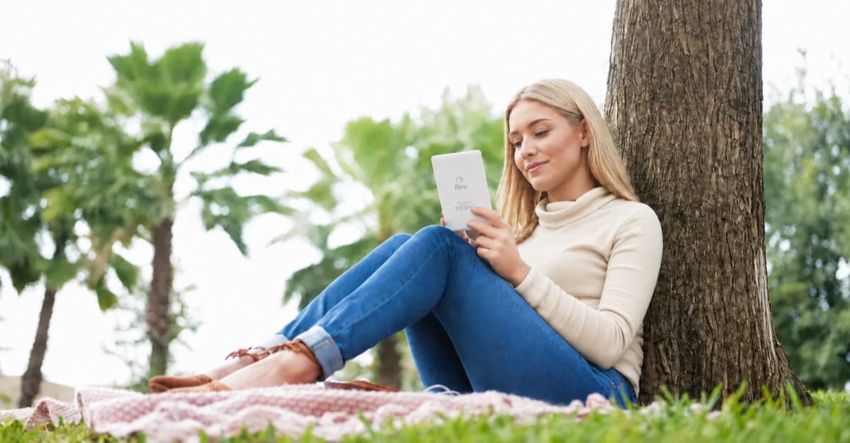 Young blonde woman reading on a Bleno device in a park